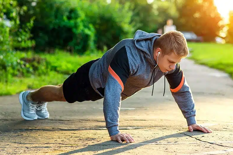 Man holding a plank position on a path outdoors