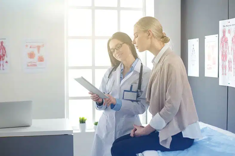 Doctor reviewing notes with a patient seated on an exam table