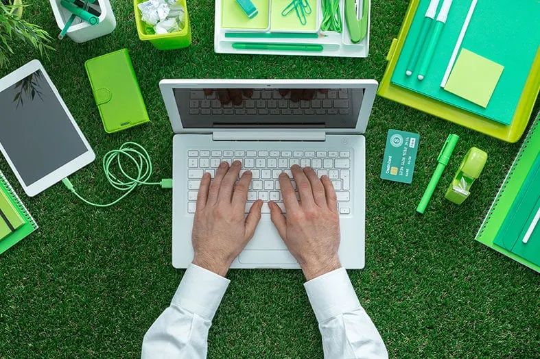 Overhead view of hands typing on a laptop surrounded by stationery