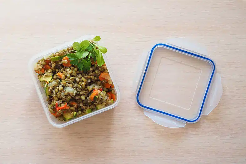 Prepared meal in a plastic container beside its lid