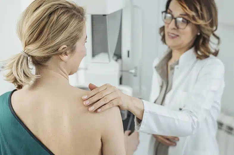 Doctor examining a woman's shoulder during a clinic visit