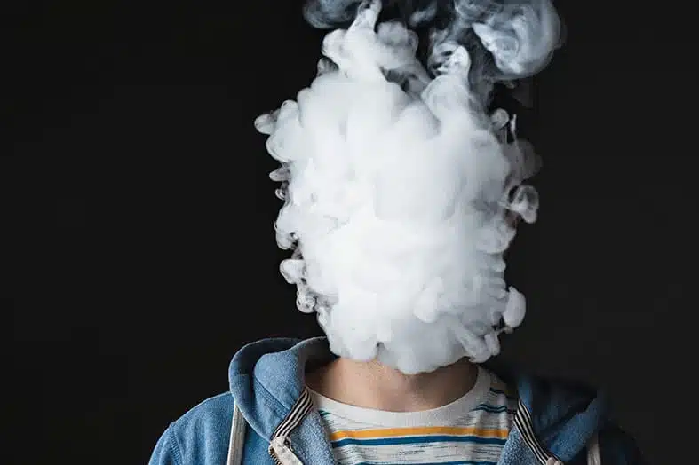 Teenager whose head is hidden by a cloud of vape smoke