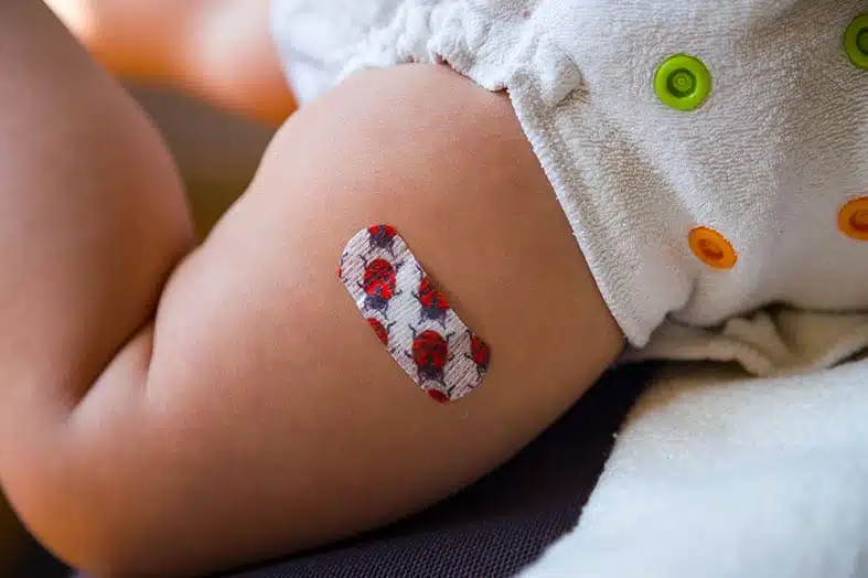 Baby's thigh with a plaster after a vaccination