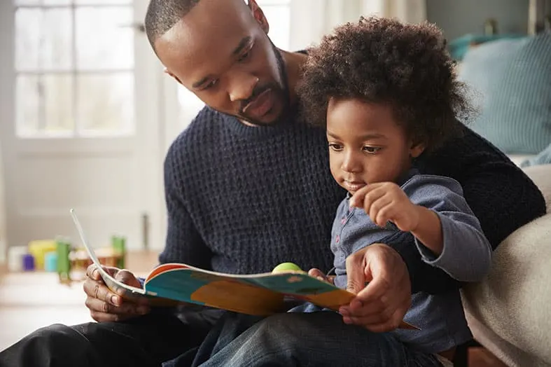 Father reading a picture book with his young child on his lap