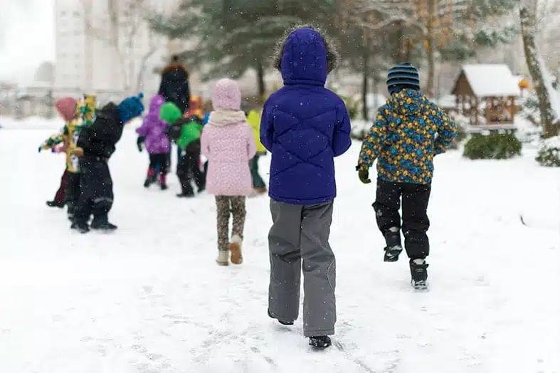 Children in winter coats walking through the snow
