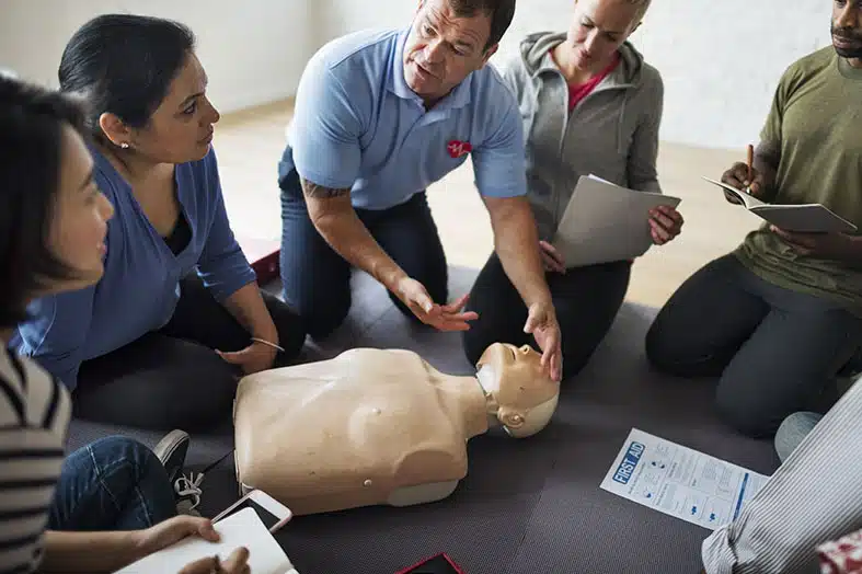 CPR class practicing chest compressions on a training manikin