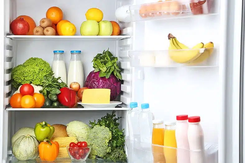 Open fridge stocked with fresh fruit, vegetables and dairy