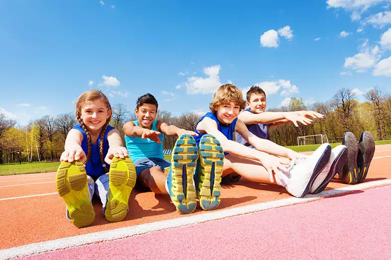 Children stretching together on a running track