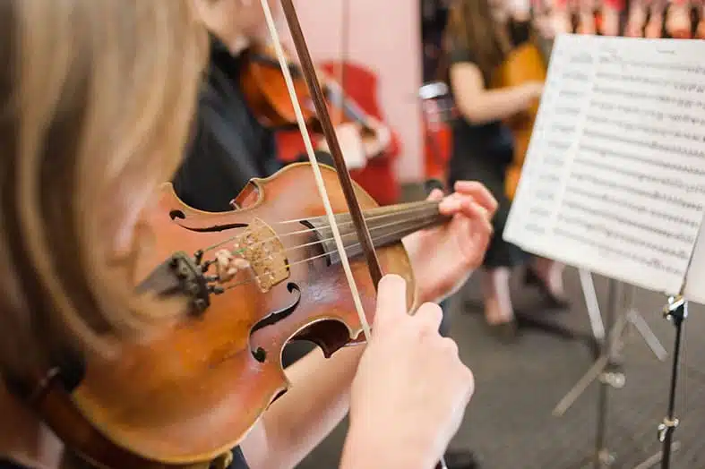 Violinist playing from sheet music in an orchestra