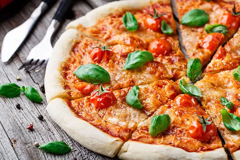Margherita pizza with basil and cherry tomatoes on a wooden board