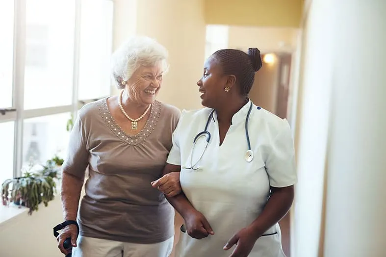 Nurse walking with an older woman who is using a cane
