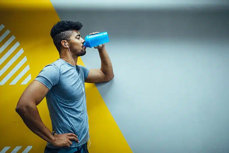Man drinking from a sports bottle after a workout