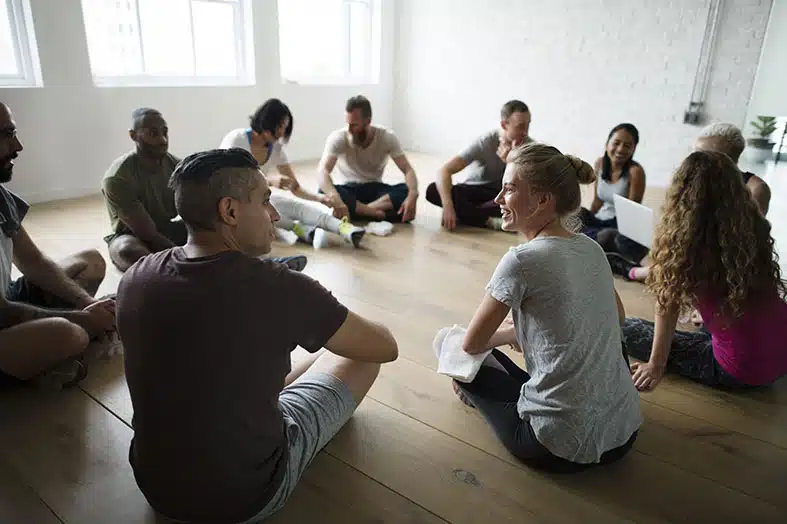 Group sitting in a circle on a studio floor talking together