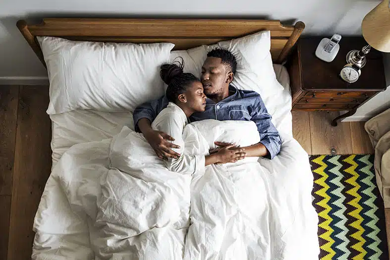 Couple sleeping soundly in bed, seen from above