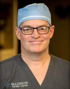 Surgeon in a blue cap and grey Madison Surgery Center scrubs