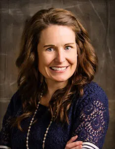 Madisonhealth staff portrait: woman with long auburn hair in a navy lace top