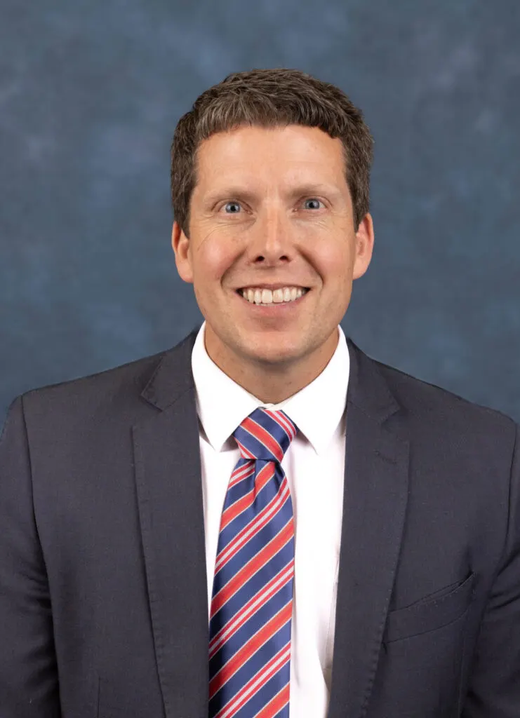 Madisonhealth staff portrait: man in a dark suit with a red and blue striped tie
