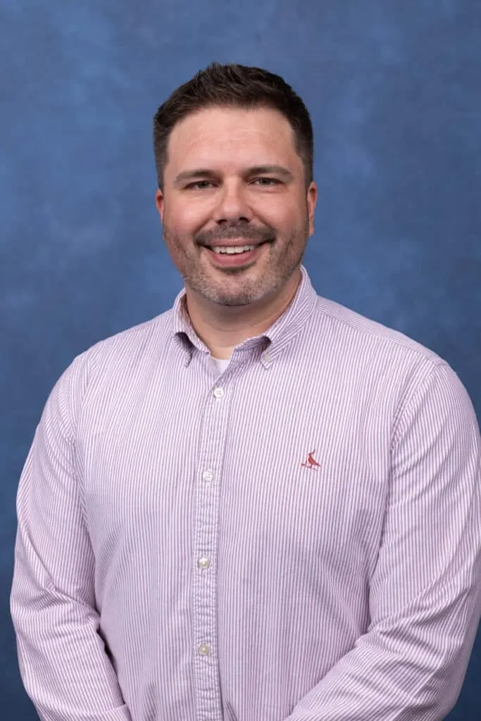 Madisonhealth staff portrait: man in a lavender striped button-down against a blue backdrop