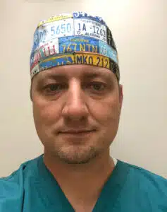 Surgeon in a licence plate print surgical cap and teal scrubs