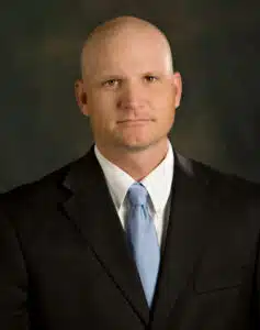 Madisonhealth staff portrait: bald man in a black suit and light blue tie