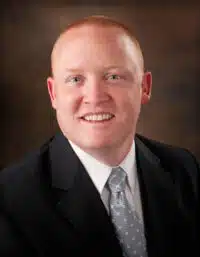 Madisonhealth staff portrait: man in a black suit and grey patterned tie