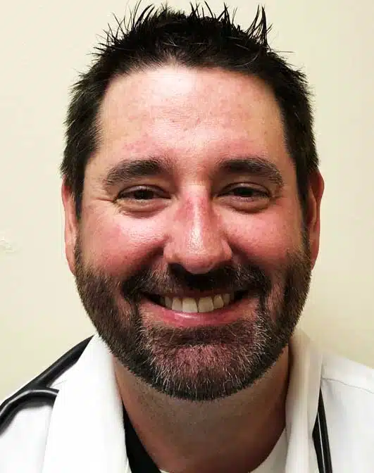 Madisonhealth physician portrait: bearded man in a white coat with a stethoscope