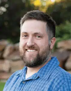 Madisonhealth staff portrait: bearded man in a blue checked shirt outdoors