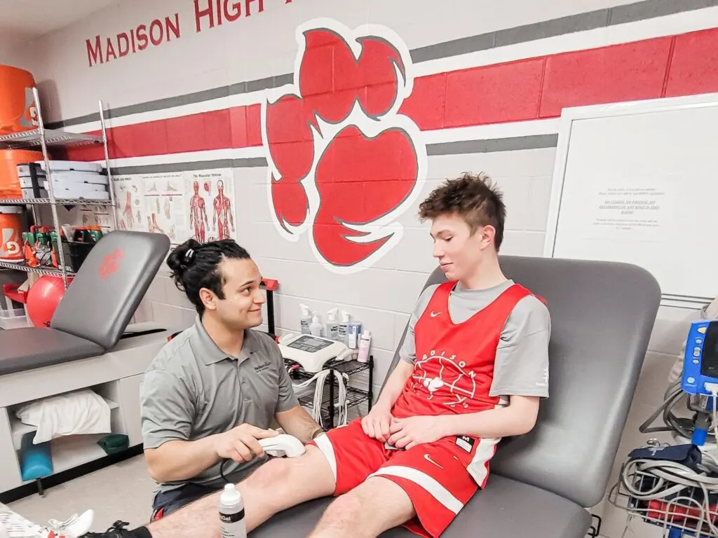 Athletic trainer treating a Madison High School athlete's leg in the training room