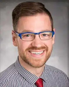 Madisonhealth staff portrait: man with blue glasses in a checked shirt and red tie