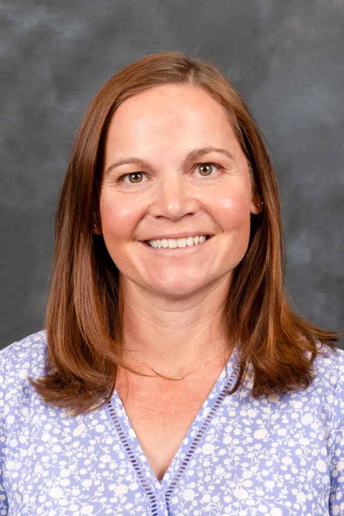 Madisonhealth provider portrait: woman with auburn hair in a lavender floral top