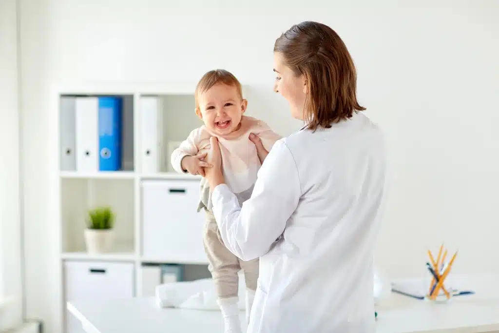 Doctor holding a laughing baby during a well-child visit