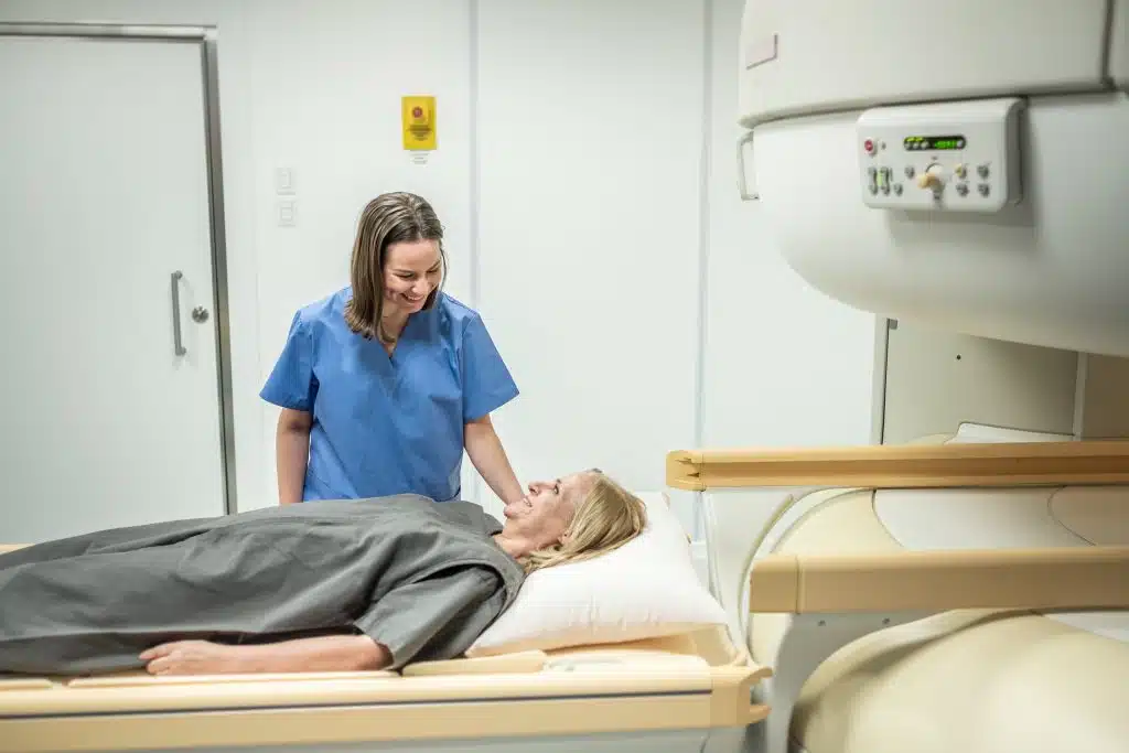 Technologist reassuring a patient lying on the table before a CT scan