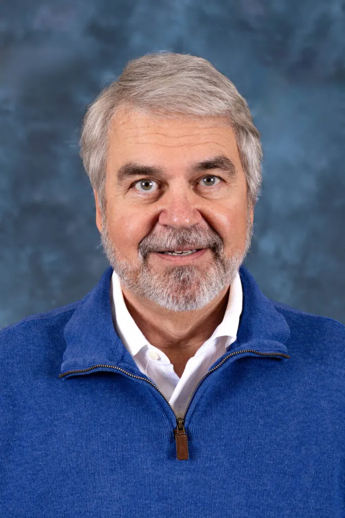 Madisonhealth physician portrait: man with grey hair and beard in a blue quarter-zip
