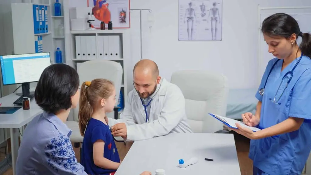 Doctor and nurse meeting with a mother and her young daughter in a clinic room