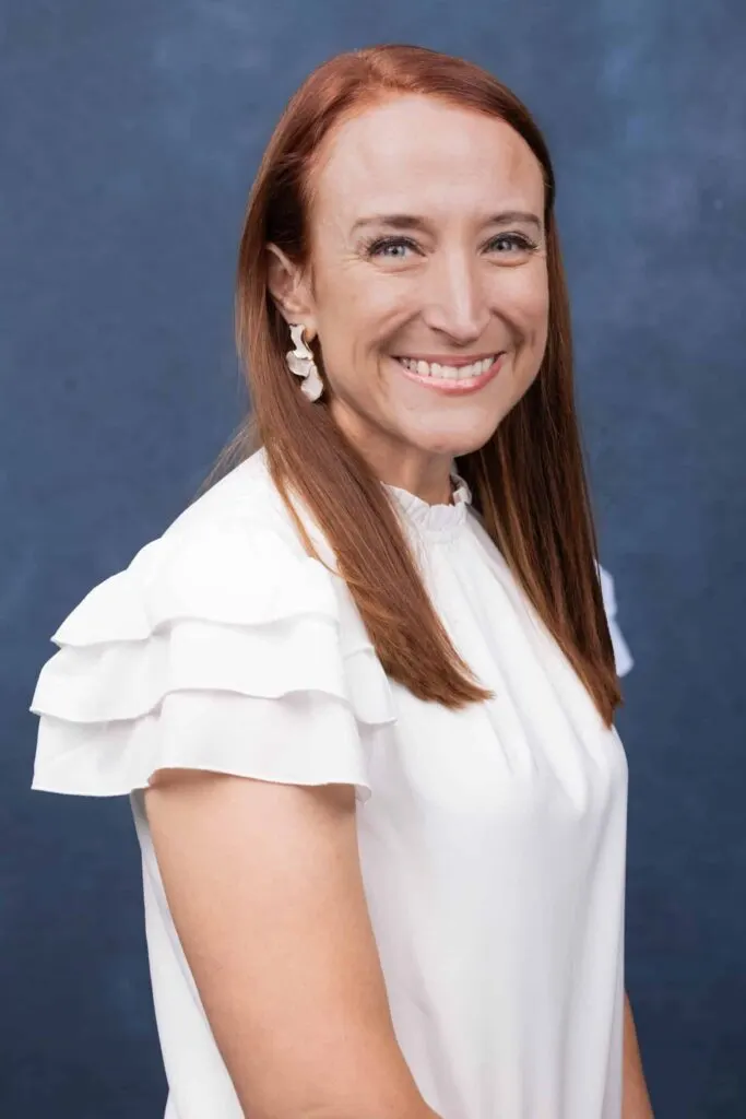 Madisonhealth staff portrait: woman with long red hair in a white ruffled blouse