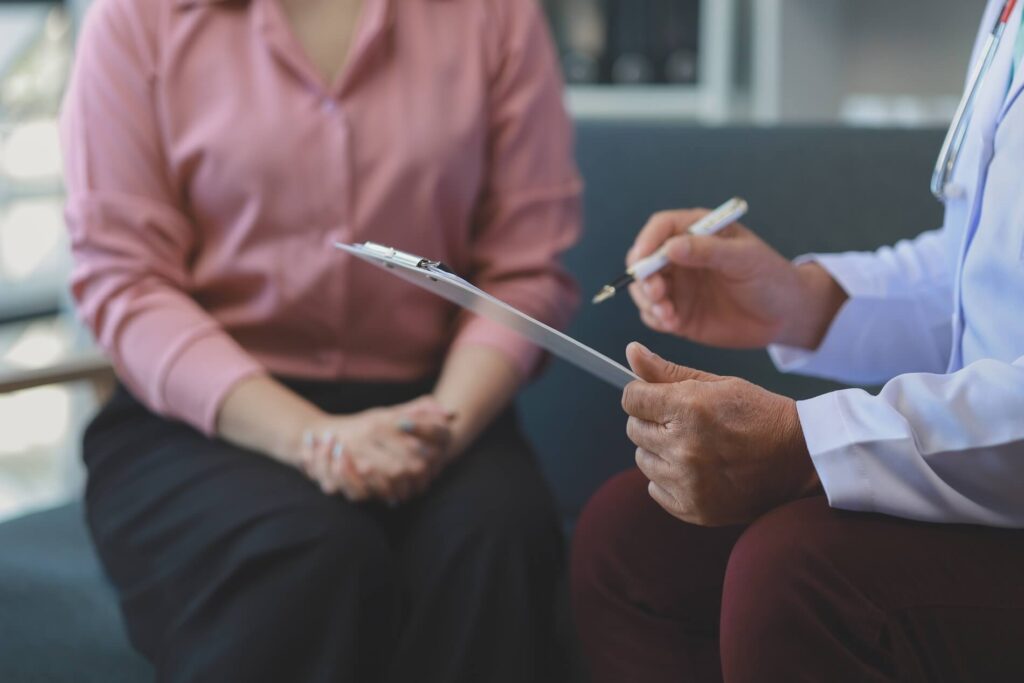 A woman sits across from a doctor in a calm, private setting during a psychiatric evaluation session.