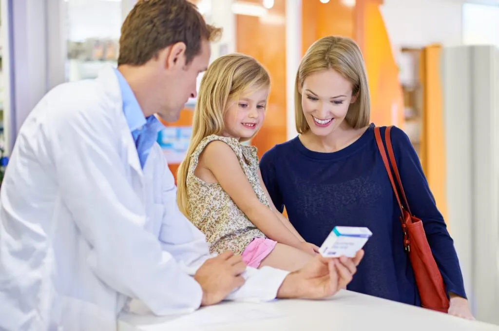 Pharmacist handing a prescription to a mother and her young daughter