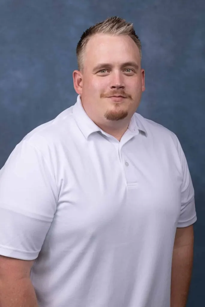 Madisonhealth staff portrait: man in a white polo shirt, blue backdrop