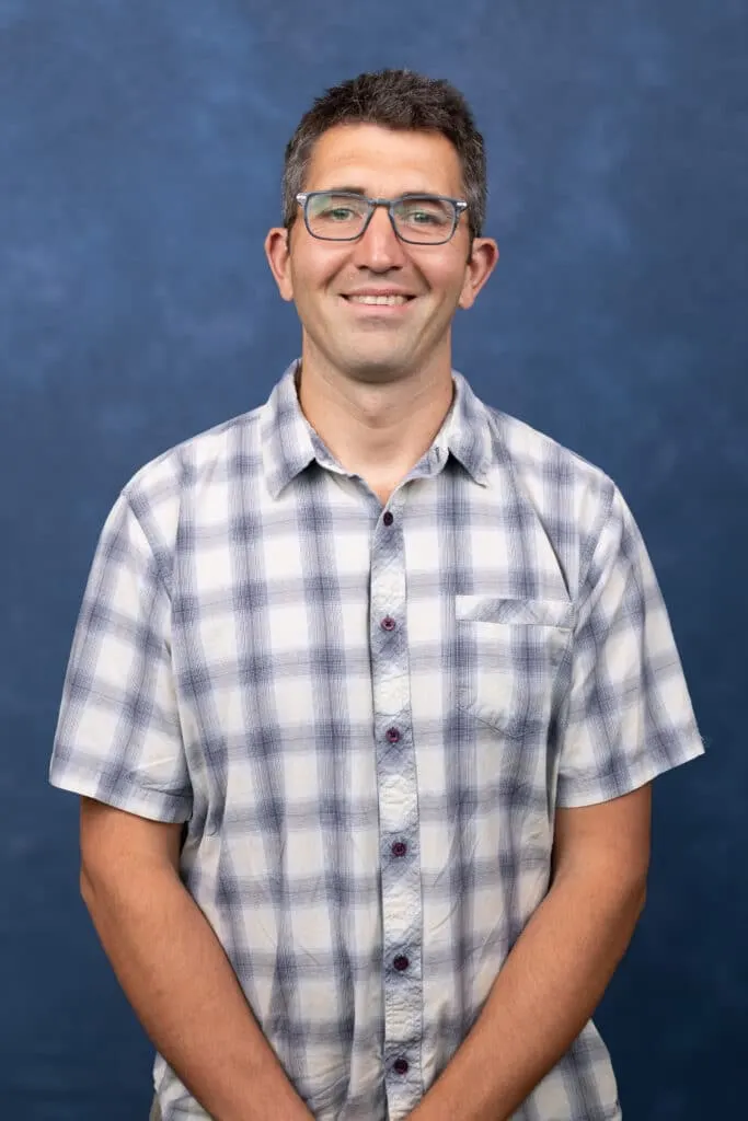 Madisonhealth staff portrait: man with glasses in a plaid short-sleeve shirt