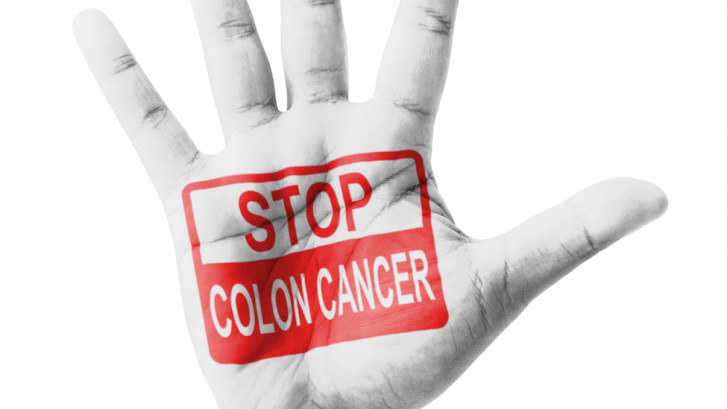 hand raised in the air with the words "stop, Colon Cancer" written on it