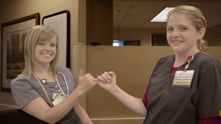 Two hospital employees pinky promising