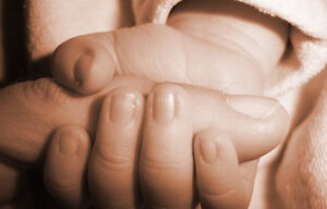 a babies hand holding the thumb of an adult